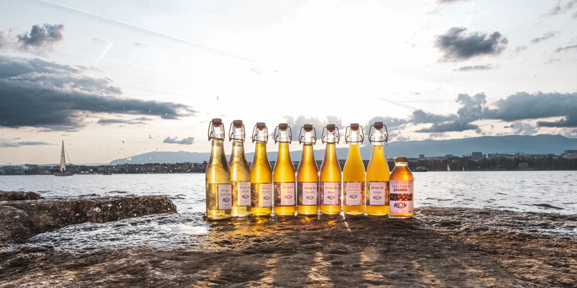 Les bouteilles ALOY alignées au bord du lac Léman au coucher du soleil