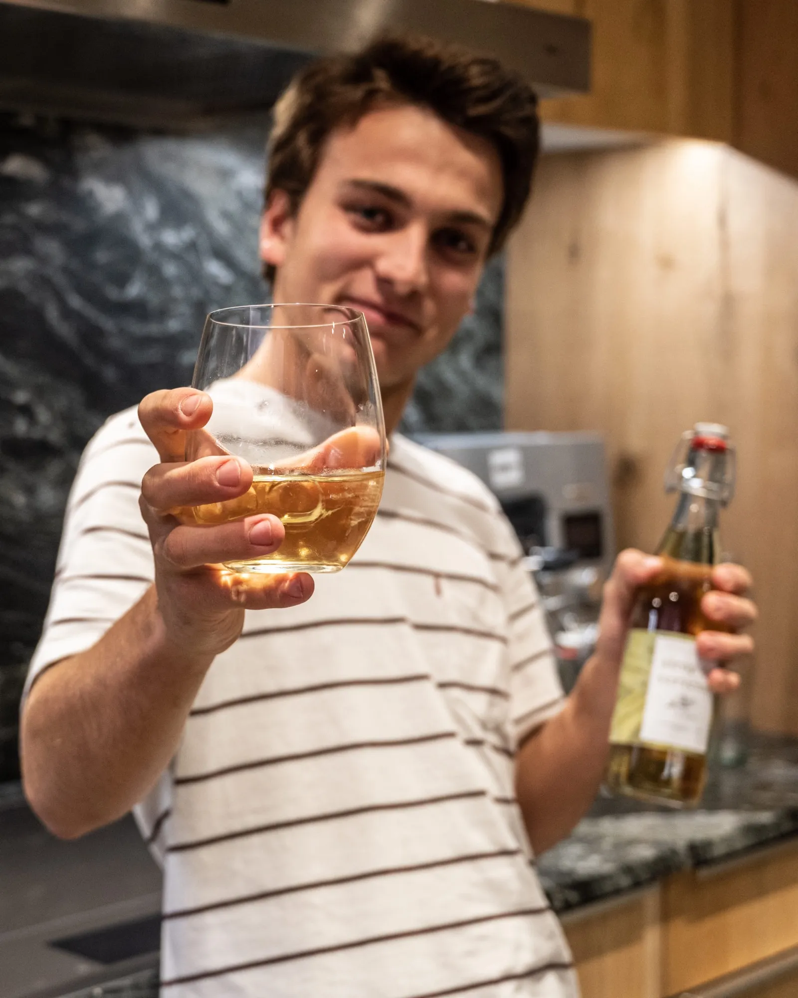 Le fondateur d’ALOY tend un verre de sirop, une bouteille à la main